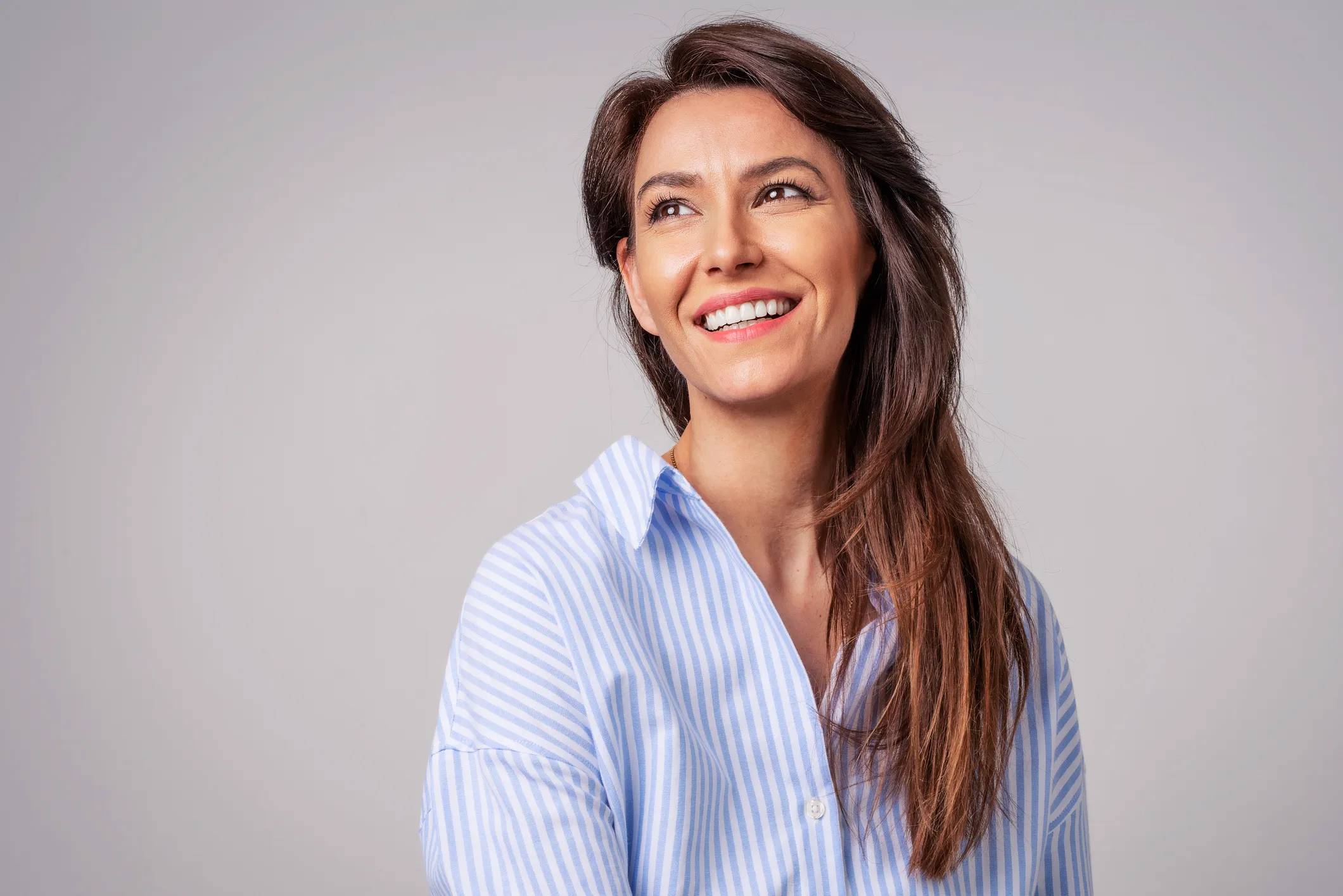 Brown haired woman smiling in a blue striped blouse