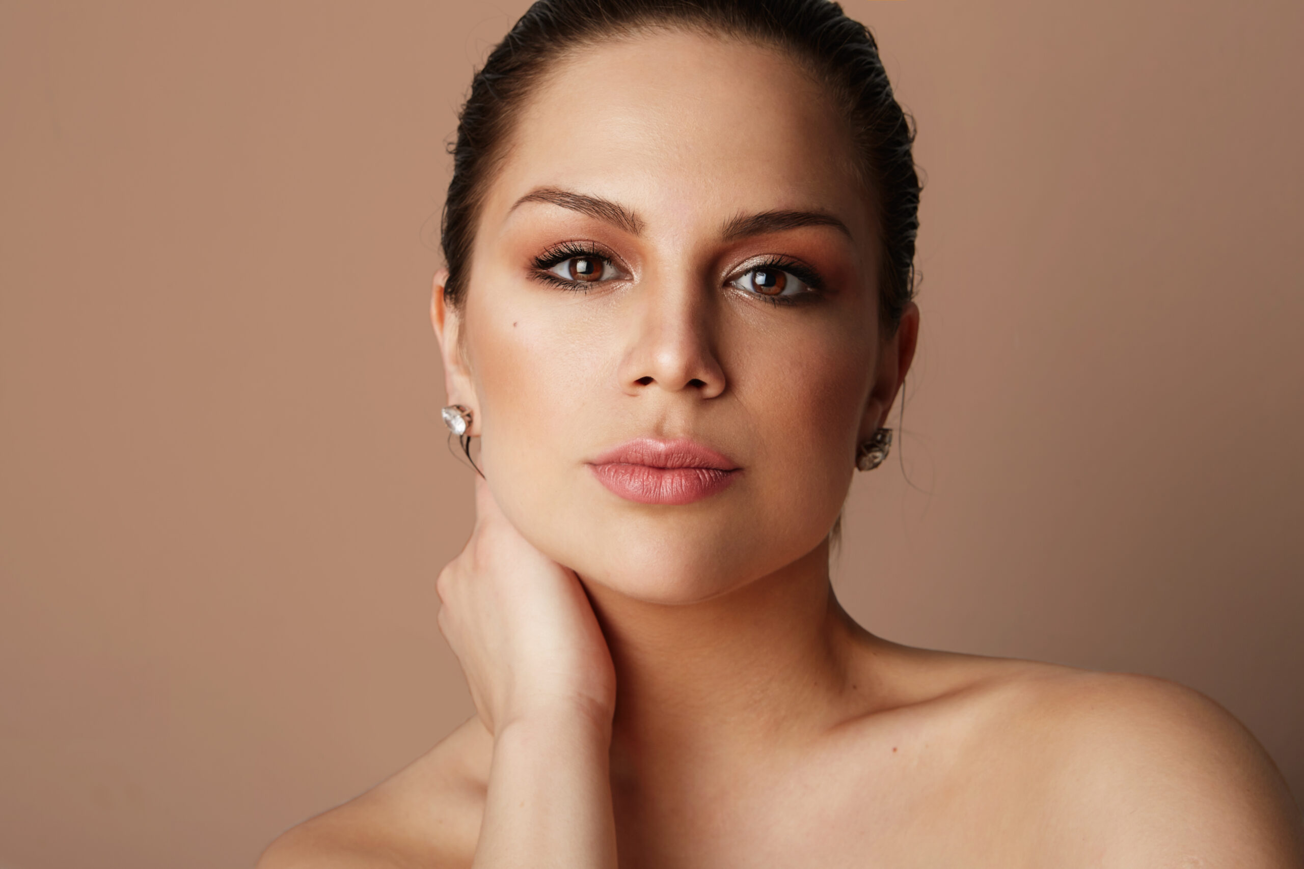 beauty women with big blue eyes and dark eyebrows looking at camera over empty background.model with light nude make up, color studio background, copy paste space, close up.